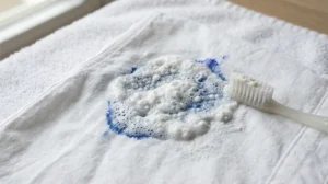 Baking soda and vinegar paste on a ball pen ink stain as a gentle method to remove ball pen stains from clothes.