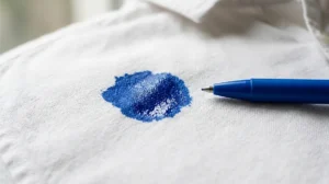 Close up of a ballpoint pen ink stain on white cotton fabric showing why the oil based ink clings to clothes.