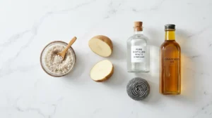 Essential supplies needed to clean a rusty cast iron skillet, including coarse salt, a halved potato, white vinegar, and a steel wool pad.