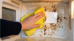 Using a soft microfiber cloth and white vinegar to wipe away heavy grease and clean inside of microwave walls.